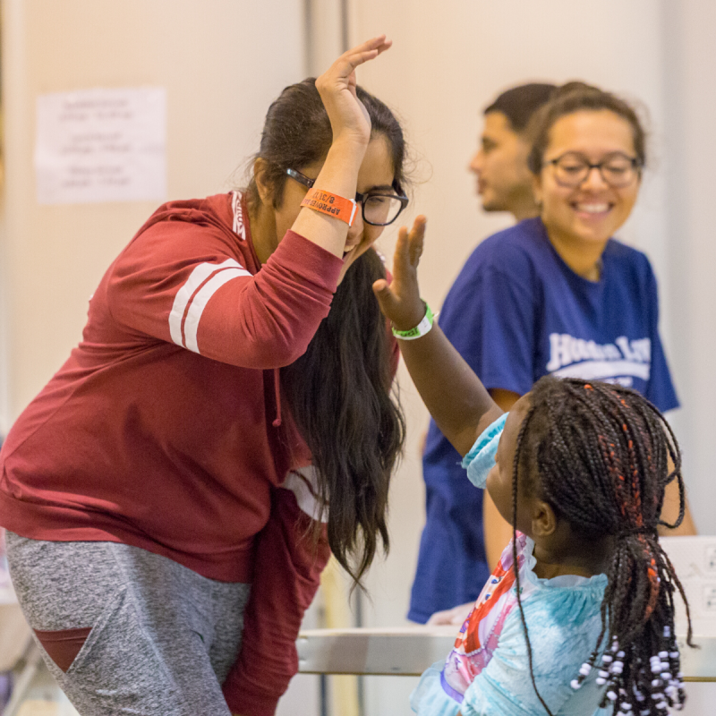 Young female participant highfiving young female child